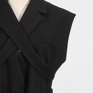 Detail of black sleeveless vest blazer with crossover collar and waist tie design