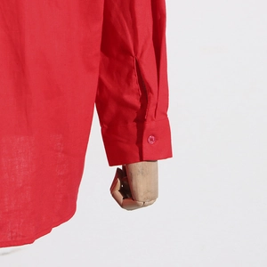 Detail view of red shirt sleeve featuring buttoned cuff and breathable fabric texture