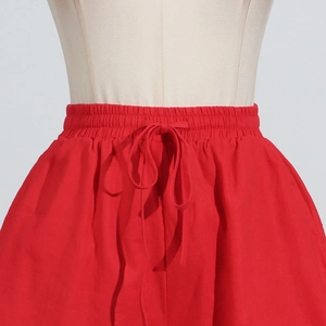 Detail of red high-waisted wide-leg trousers with elastic waistband and drawstring bow