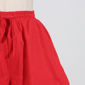 Detail of red high-waisted wide-leg shorts featuring elastic waist and drawstring cord