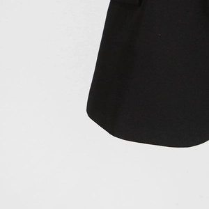 Detail view of the sleek curved hem and fine stitching on this elegant black sleeveless blazer