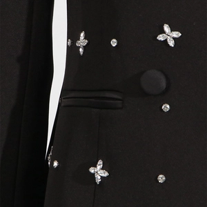 Detail of black blazer with sparkling rhinestone flower pattern and a cloth button