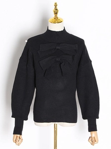 Elegant black puff sleeve knit sweater featuring decorative bows and a mock neck design