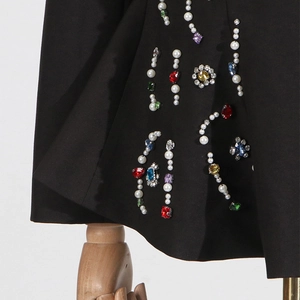 Detail of black blazer featuring colorful rhinestones and imitation pearl embellishments