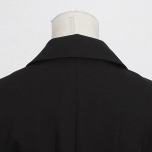 Detailed close-up of a black sleeveless blazer notch lapel and back neckline texture