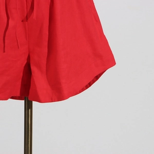 Close-up of red linen blend pants showing fabric texture and curved hem stitching details