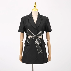 Détail d'une robe blazer noire avec nœud en strass étincelants et découpe à la taille