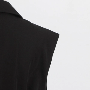 Detailed close-up of padded shoulders and notch lapels on black sleeveless blazer