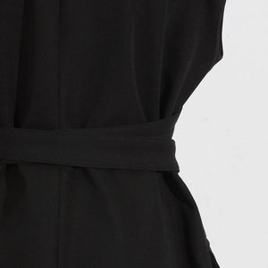 Close-up of a black sleeveless blazer jacket featuring a waist belt tie and fine texture
