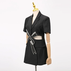 Détail d'une robe blazer avec un nœud en strass étincelant et une découpe à la taille