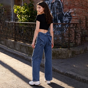 Détail du jean denim bleu à taille haute avec un grand nœud décoratif au dos