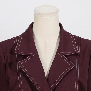 Detail der weinroten Blazerjacke mit eleganten weißen Kontrastnähten und spitzem Revers