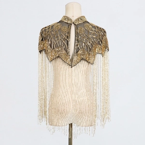 Detailed close-up of golden sequins and long beaded fringe on a luxury shawl