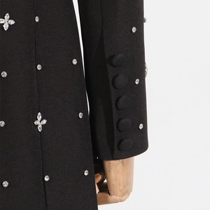 Detail of rhinestone star patterns and fabric-covered buttons on a black blazer sleeve