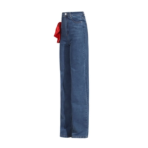 Detail view of a large red satin bow on the waist of high-rise straight-leg blue jeans