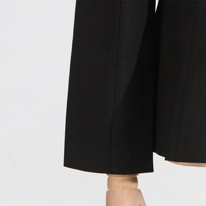 Detail of the hem on black slim-fit trousers showing precise stitching and woven fabric