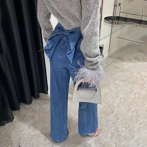 Gros plan sur un jean bleu foncé taille haute avec un grand nœud décoratif au dos