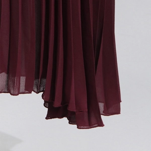 Close-up of wine red pleated chiffon skirt showing detailed vertical pleats and hem finish