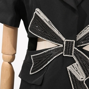 Détail de la découpe à la taille avec nœud en cristaux 3D sur robe blazer noire