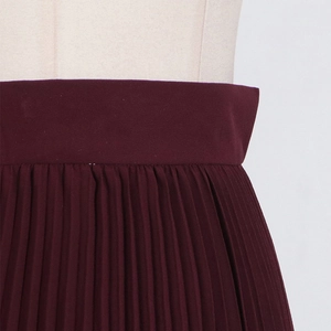Detail of high waist dark red pleated skirt showing the fine texture and craftsmanship