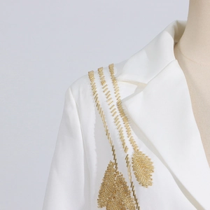 Detail of white blazer with intricate gold leaf beadwork embroidery on the shoulder