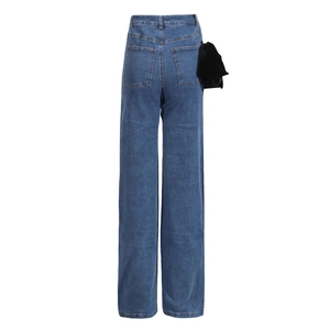 Detail of high waist denim jeans with a black velvet bow on the back pocket area