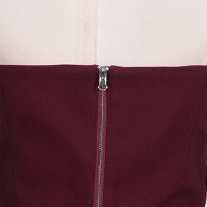Detail view of the silver metal zipper on the back of a wine red off-shoulder top
