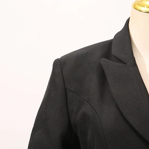 Détail du revers à encoche et des épaules rembourrées sur une veste de tailleur noire