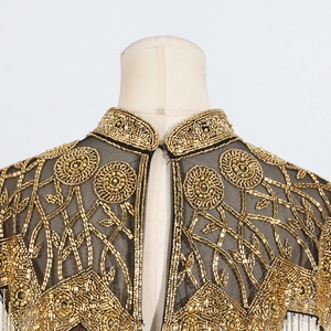 Close-up of ornate gold beadwork and intricate floral embroidery on black mesh shawl