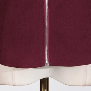Detailed view of silver metal zipper on burgundy fabric vest shown on a mannequin