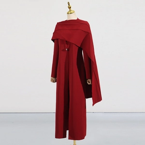 Détail d'un manteau long rouge foncé élégant avec cape drapée et bouton en diamant brillant