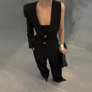 Detail of avant-garde black asymmetrical blazer set with high-waist wide-leg trousers