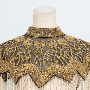 Detail of handmade gold bead embroidery and metallic fringe on a black mesh shawl