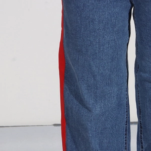 Detail of blue denim pants with red contrast side stripe stitching and twill texture