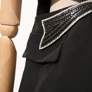 Détail d'une robe blazer noire avec bordure en strass argentés et broderie perlée