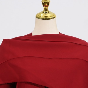Vue détaillée du col et du design multicouche en tissu rouge foncé sur ce trench-coat