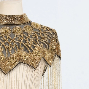 Detail of heavy bead embroidery and golden fringe tassels on a vintage black mesh cape