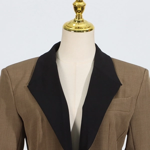 Close-up of contrast black peak lapel and shoulder pads on brown suit blazer