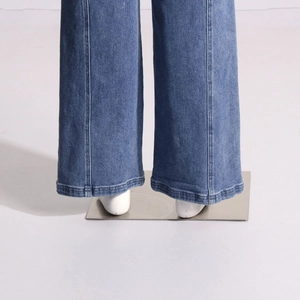 Détail du pantalon large en jean bleu avec couture verticale et revers à l'ourlet