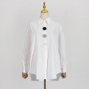 Detail of white rhinestone shirt featuring unique floral buttons on the placket