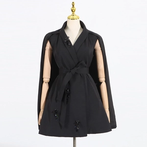 Detail of waist belt and 3D sequin flower embellishments on a black cloak suit jacket