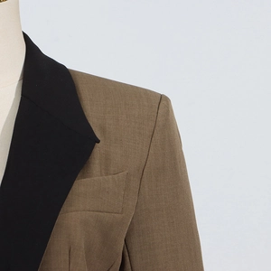 Close-up of contrast notch lapel and structured shoulder on a brown and black blazer