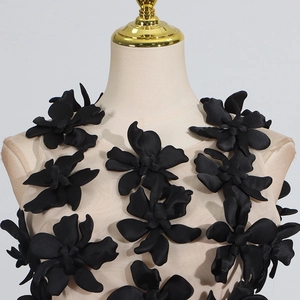 Close-up of 3D black fabric flowers on beige mesh top with elegant round neckline