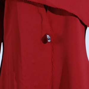 Détail d'un manteau rouge en sergé avec bord brut et bouton argenté poli