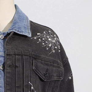 Détails d'une veste en jean grise avec motifs en strass brillants et col contrasté