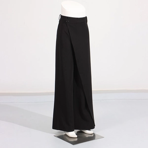 Detail view of high-waist black wide-leg trousers with wrap-front design and side button closure
