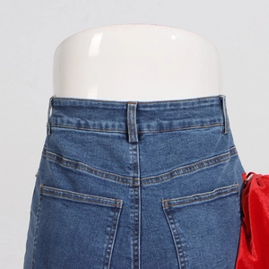 Detail of high waist denim jeans featuring a red velvet bow and contrast stitching