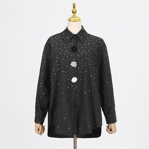 Detailed view of rhinestone embellishments and 3D floral accents on a black shirt