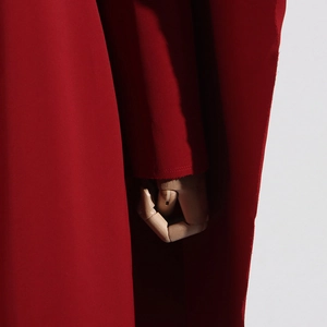 Détail du trench-coat rouge montrant le tissu tissé de qualité et la finition du poignet