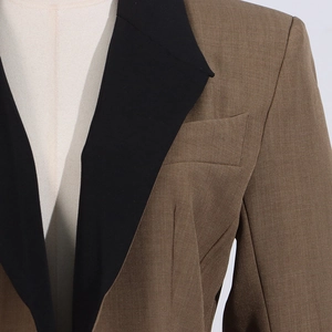 Detail of a brown suit jacket showing the black notch lapel and fine fabric texture